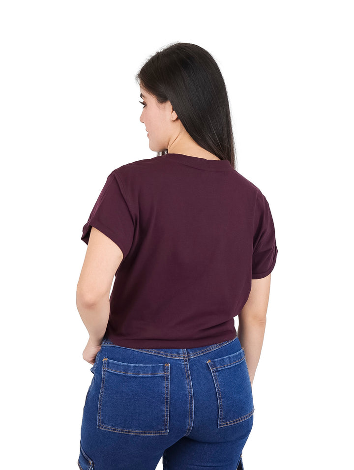Mujer vistiendo camiseta color borgoña DKNY de corte boxy con nudo en la cintura.
