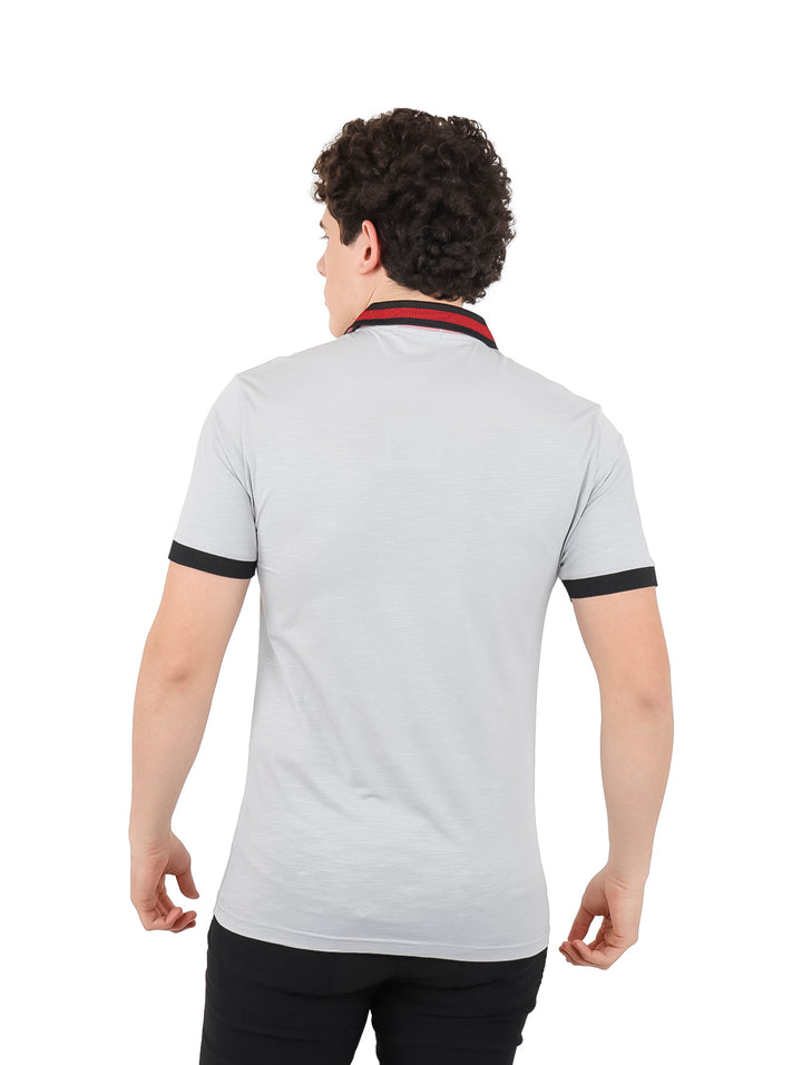 Hombre vistiendo playera polo color gris con detalles en negro y rojo en el cuello y mangas.