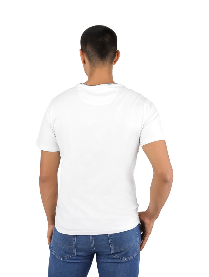 Hombre vistiendo camiseta blanca DKNY con panel horizontal negro en el pecho y cuello contrastado.