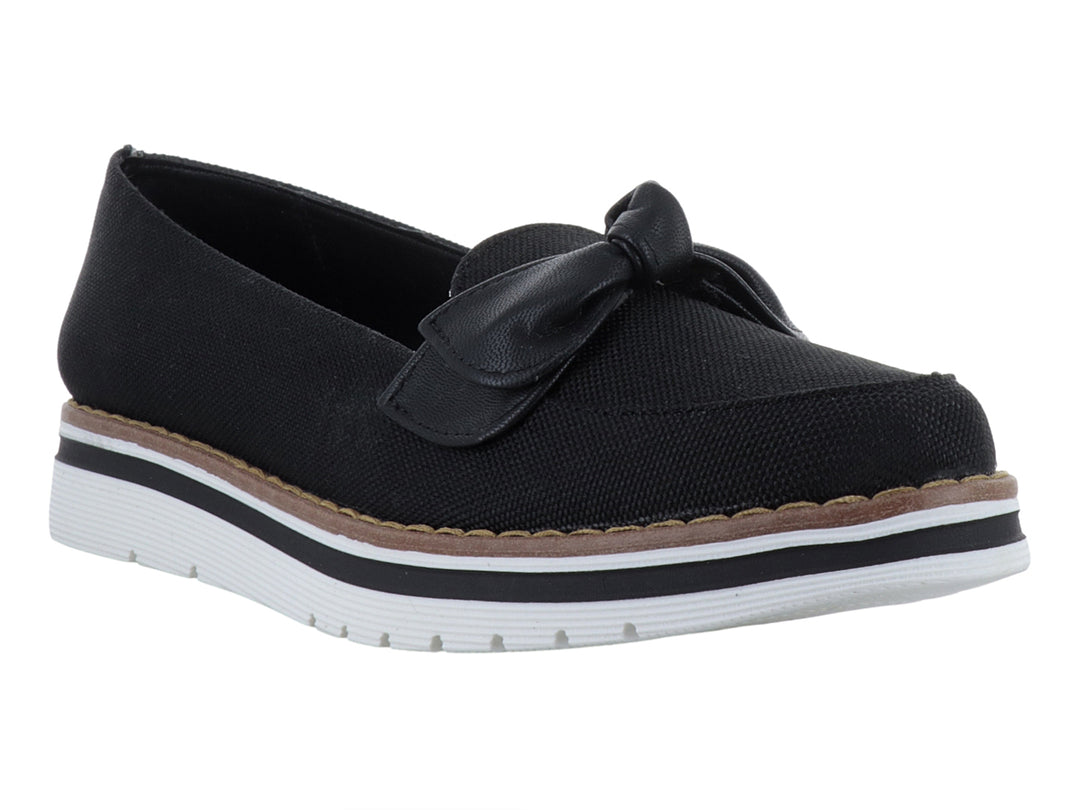 Zapato plano color negro con moño decorativo y suela blanca con detalle café.
