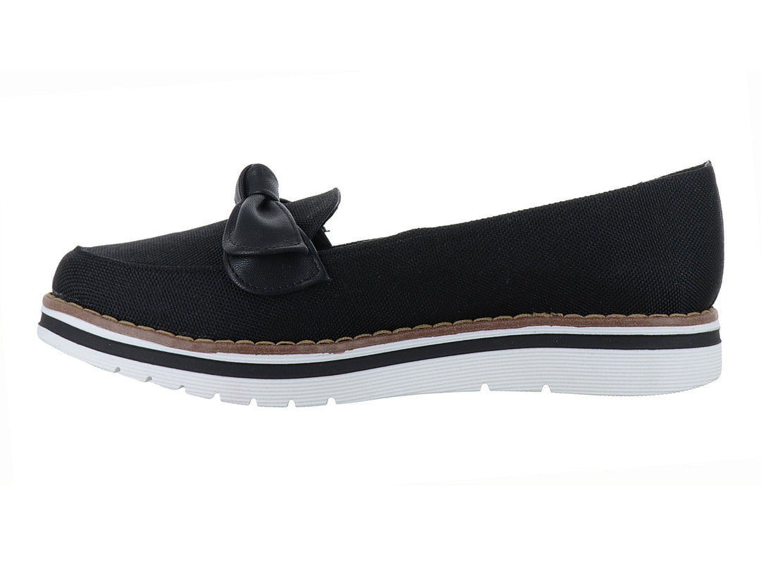 Zapato plano color negro con moño decorativo y suela blanca con detalle café.
