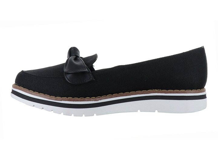 Zapato plano color negro con moño decorativo y suela blanca con detalle café.