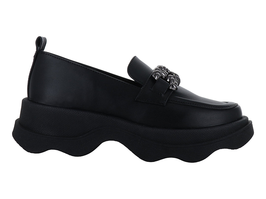 Zapato loafer negro con suela ancha ondulada y detalle metálico decorativo en la parte superior.