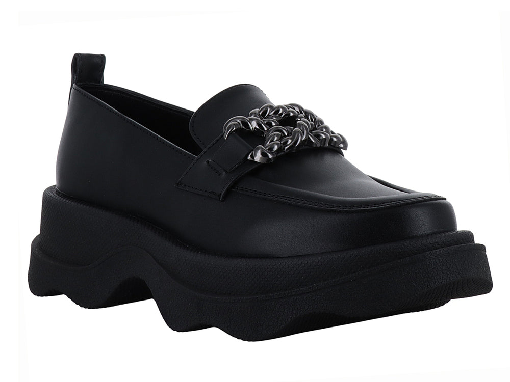 Zapato loafer negro con suela ancha ondulada y detalle metálico decorativo en la parte superior.
