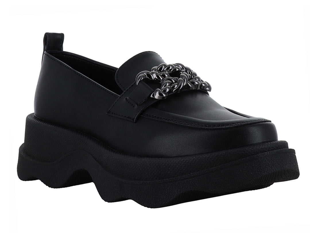 Zapato loafer negro con suela ancha ondulada y detalle metálico decorativo en la parte superior.