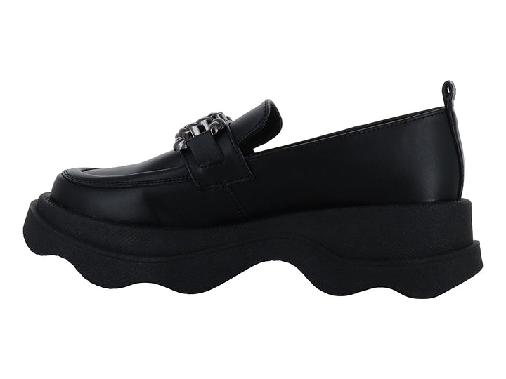 Zapato loafer negro con suela ancha ondulada y detalle metálico decorativo en la parte superior.