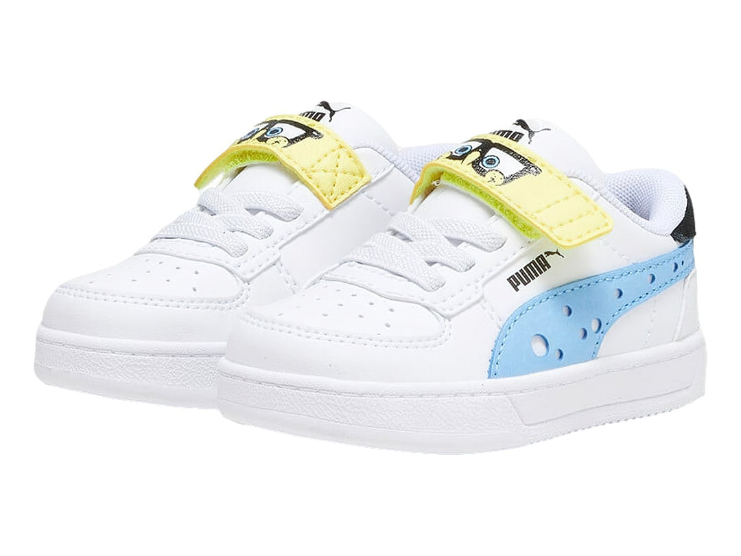 Tenis PUMA blancos para niño con detalles en negro y amarillo, cierre de agujetas y correa de velcro.
