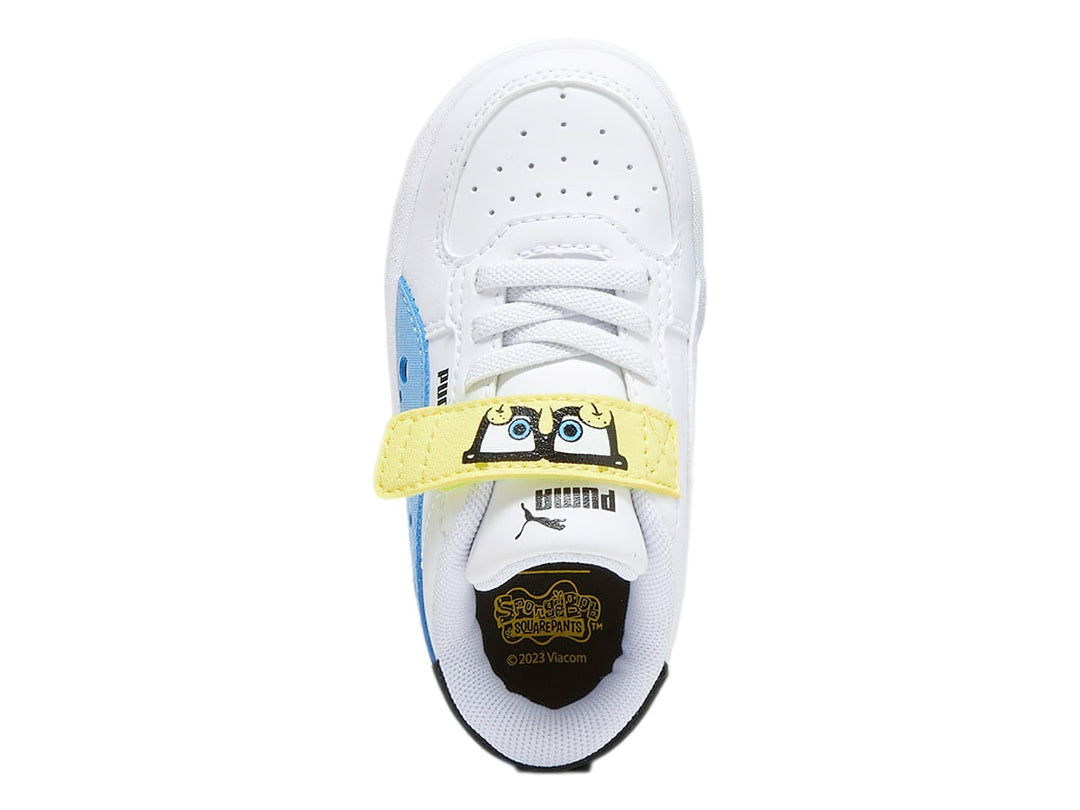 Tenis PUMA blancos para niño con detalles en negro y amarillo, cierre de agujetas y correa de velcro.