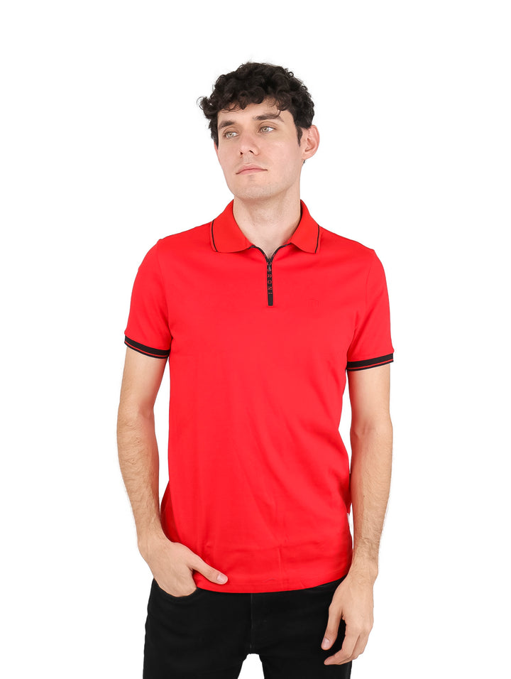 Hombre vistiendo playera polo roja con detalles en negro y cierre frontal.