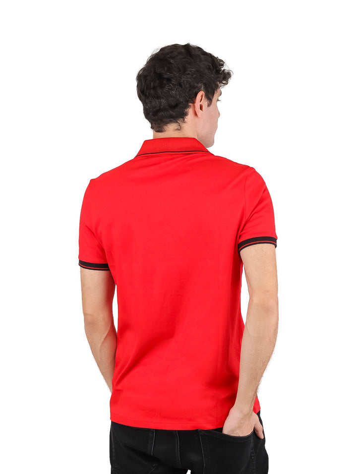 Hombre vistiendo playera polo roja con detalles en negro y cierre frontal.