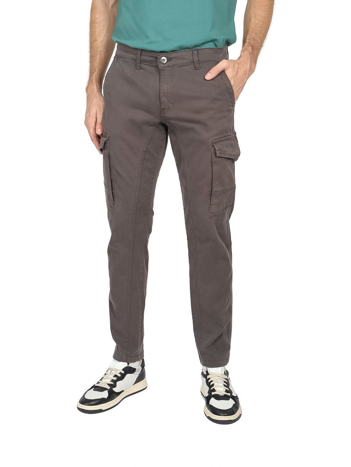 Hombre vistiendo pantalón slim fit color gris oscuro con bolsillos laterales estilo cargo.