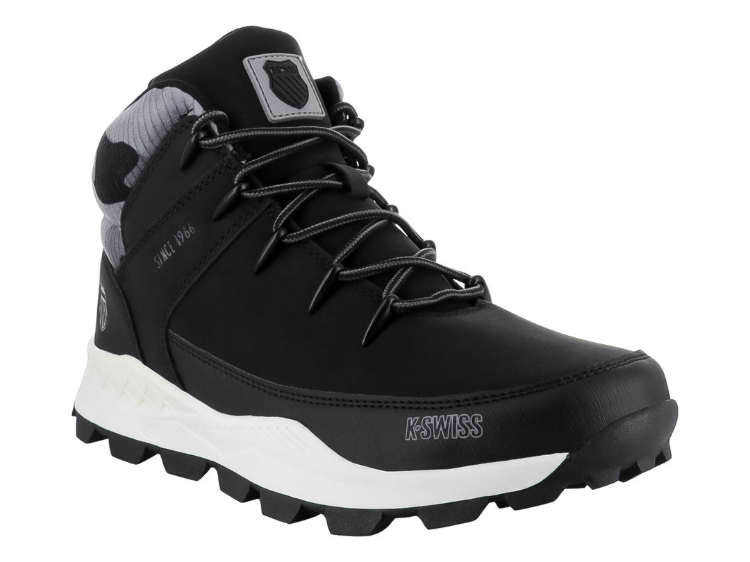 Bota K-Swiss color negro con suela blanca y detalle de camuflaje gris en el tobillo.