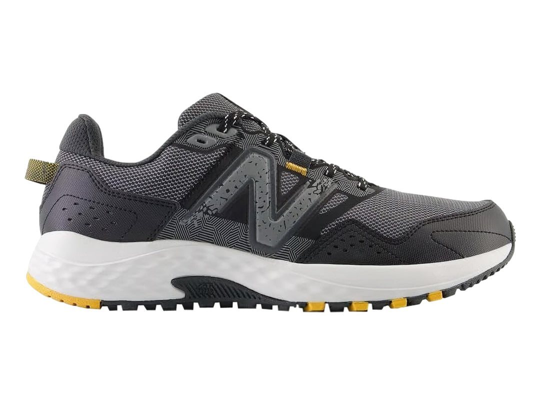 Tenis deportivos New Balance color gris Castlerock con suela blanca y detalles amarillos.