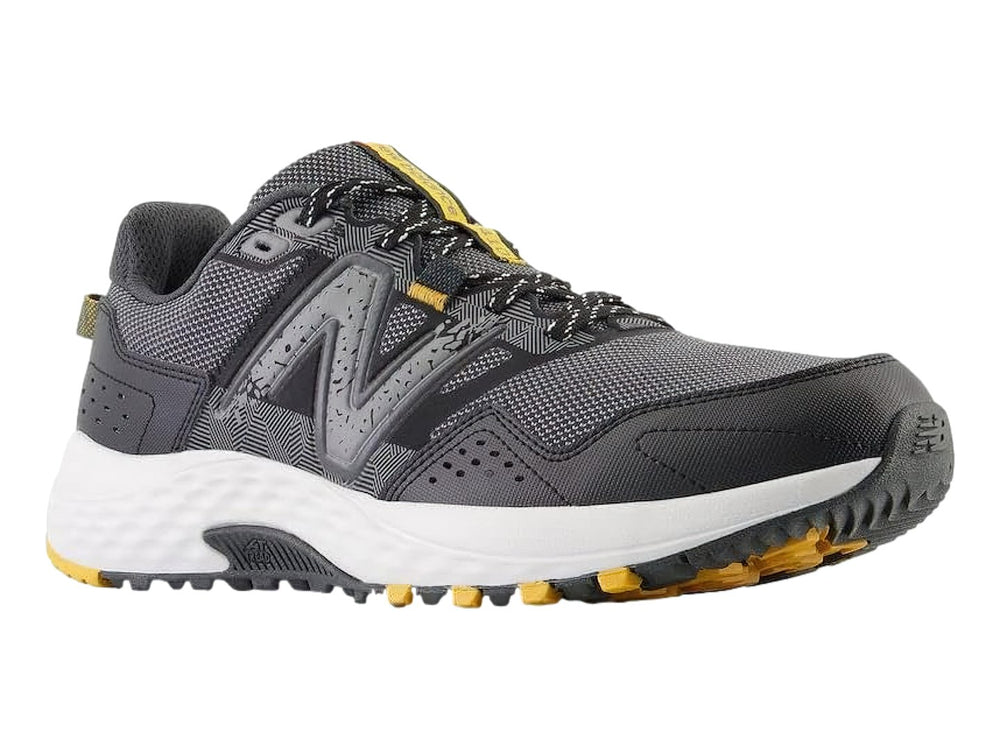 Tenis deportivos New Balance color gris Castlerock con suela blanca y detalles amarillos.