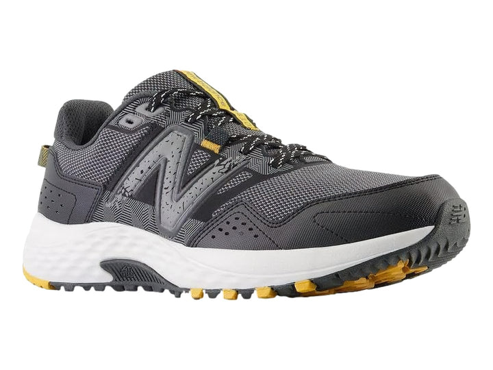Tenis deportivos New Balance color gris Castlerock con suela blanca y detalles amarillos.