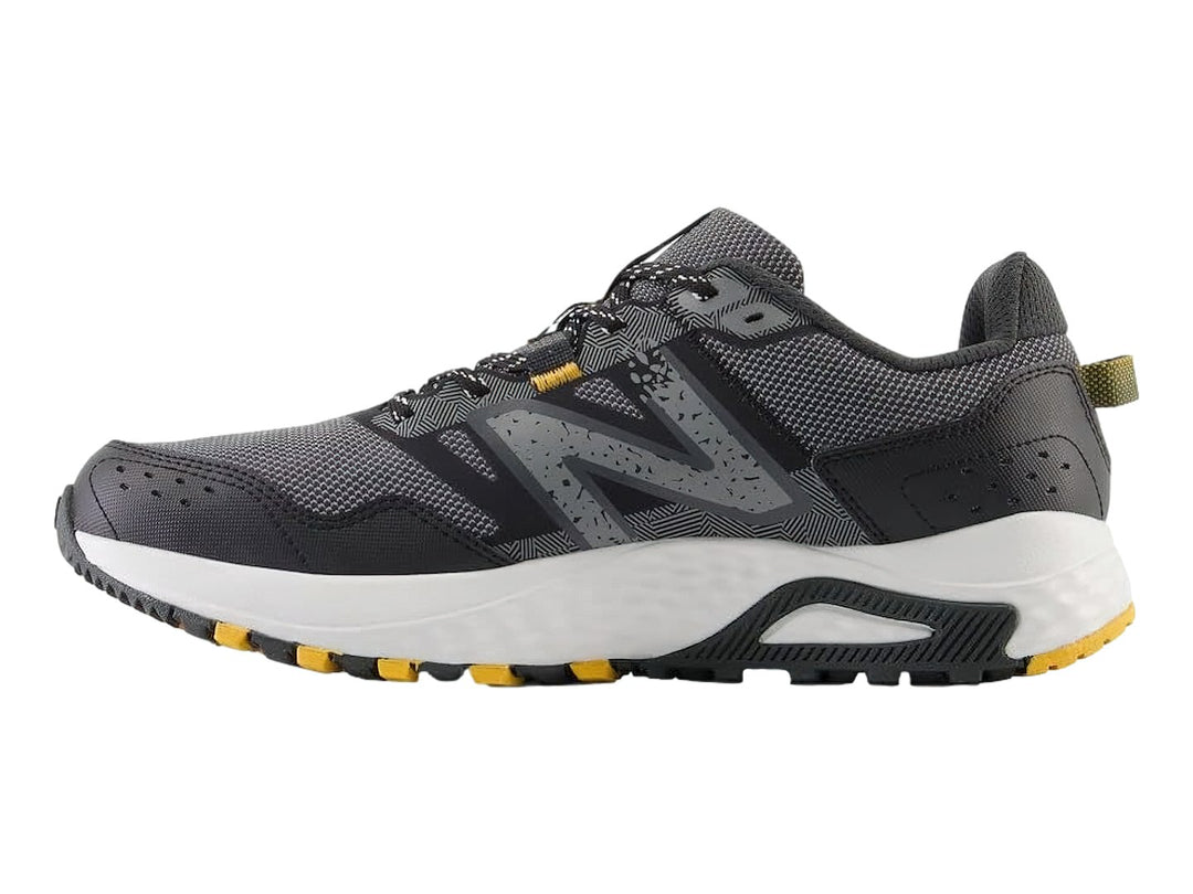 Tenis deportivos New Balance color gris Castlerock con suela blanca y detalles amarillos.