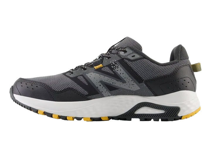 Tenis deportivos New Balance color gris Castlerock con suela blanca y detalles amarillos.