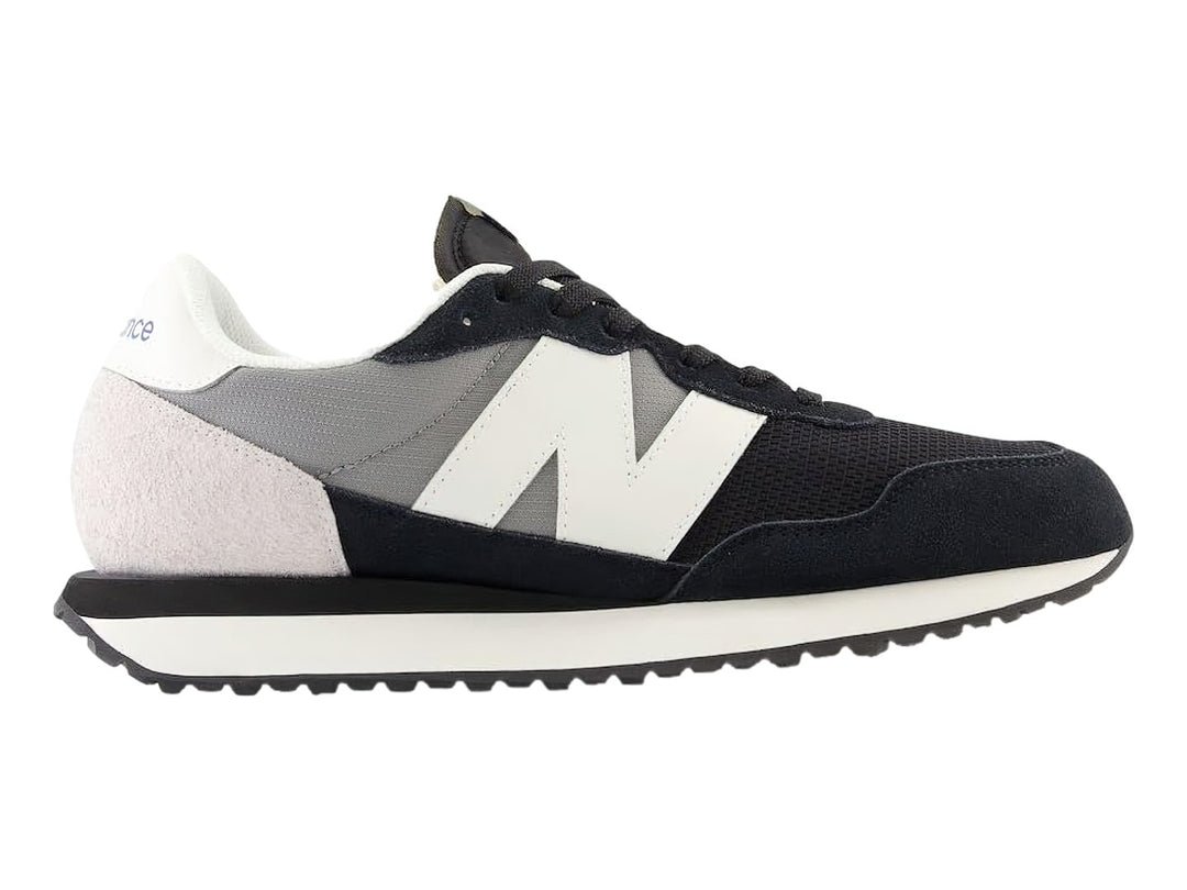 Tenis New Balance negros con detalles en blanco y gris y suela blanca dentada.