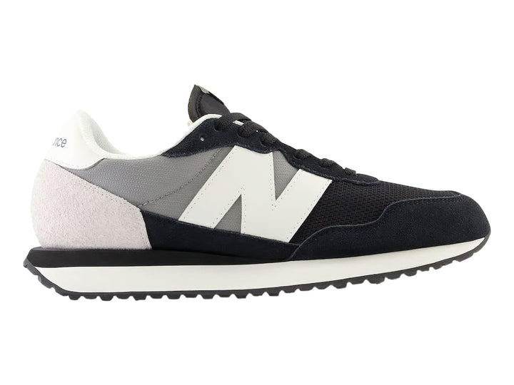 Tenis New Balance negros con detalles en blanco y gris y suela blanca dentada.