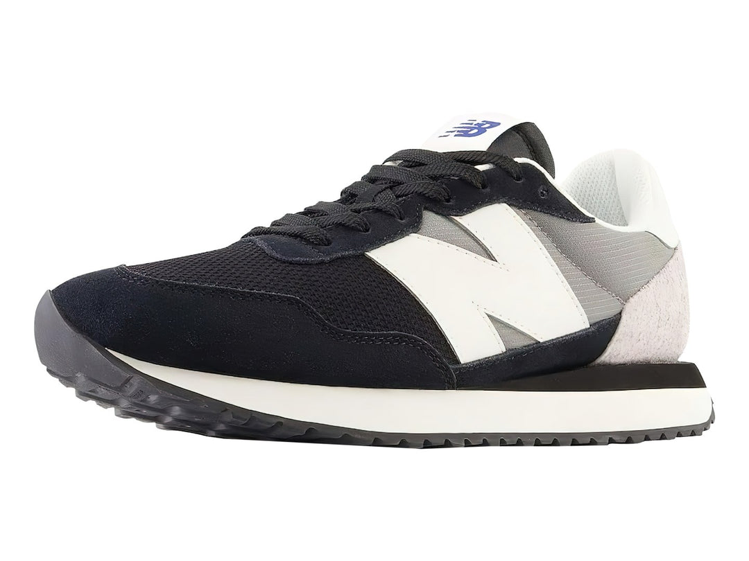Tenis New Balance negros con detalles en blanco y gris y suela blanca dentada.
