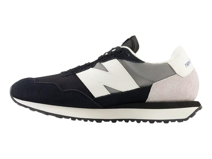 Tenis New Balance negros con detalles en blanco y gris y suela blanca dentada.