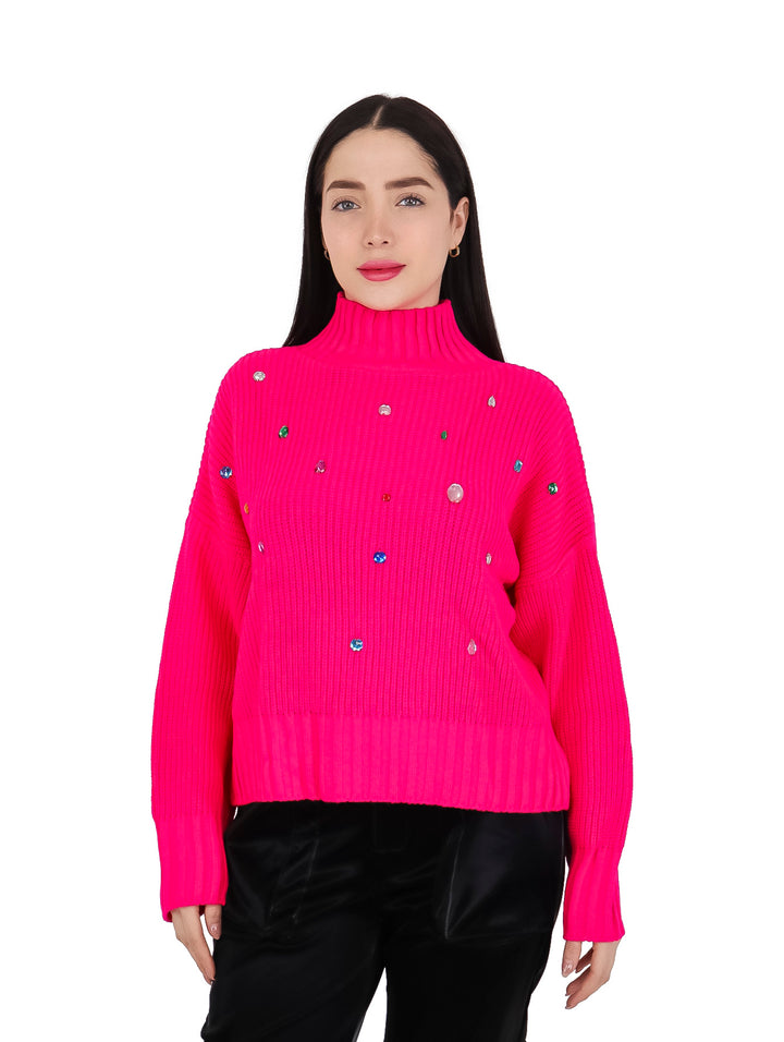 Mujer vistiendo un suéter fucsia de cuello alto adornado con piedras coloridas.