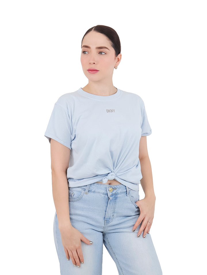 Mujer vistiendo camiseta DKNY color azul claro con nudo en la cintura y pantalones vaqueros claros.