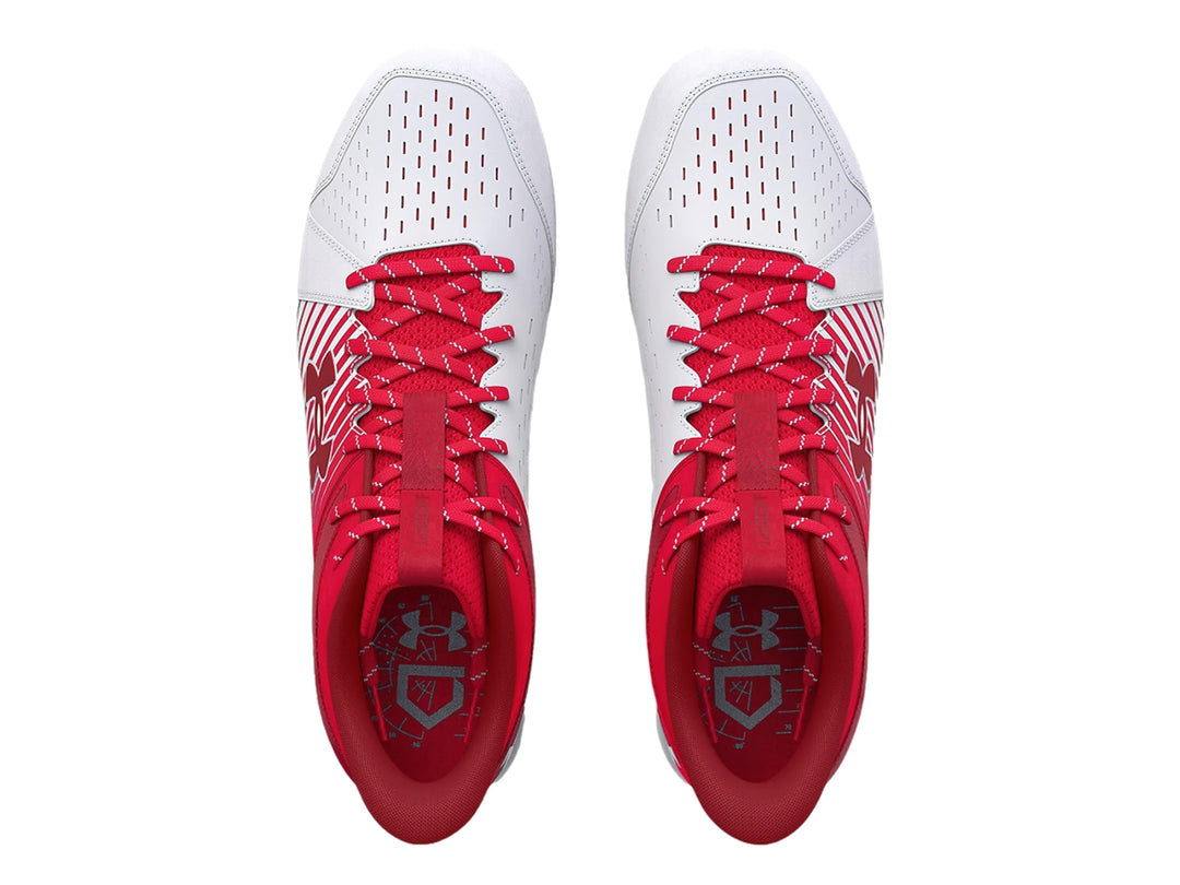 Zapato deportivo Under Armour color rojo y blanco con suela de tacos para deporte.