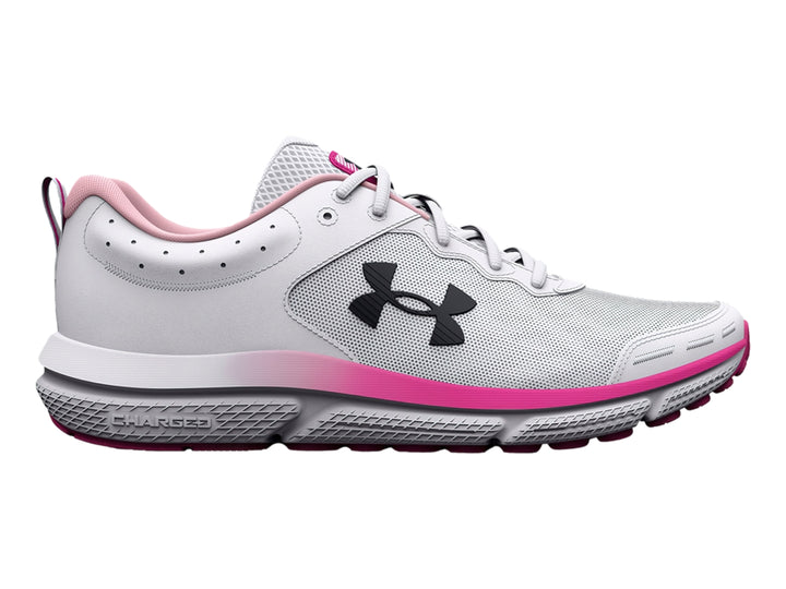 Tenis deportivos Under Armour blancos con detalles en rosa y logo negro, vista lateral.