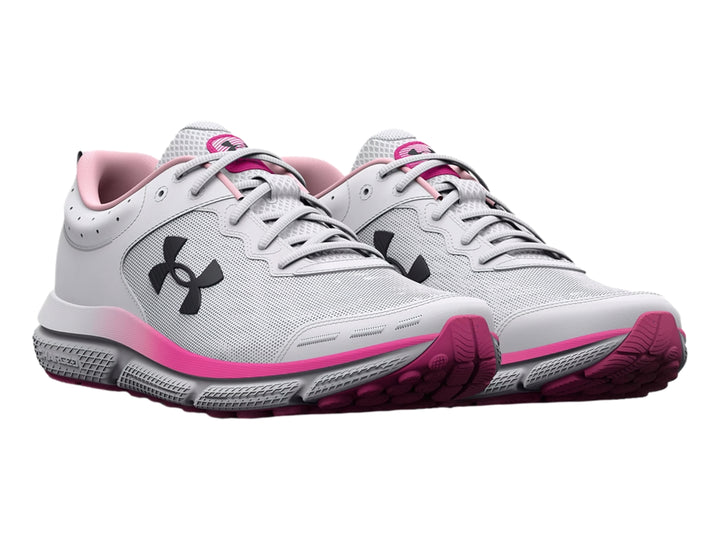 Tenis deportivos Under Armour blancos con detalles en rosa y logo negro, vista lateral.