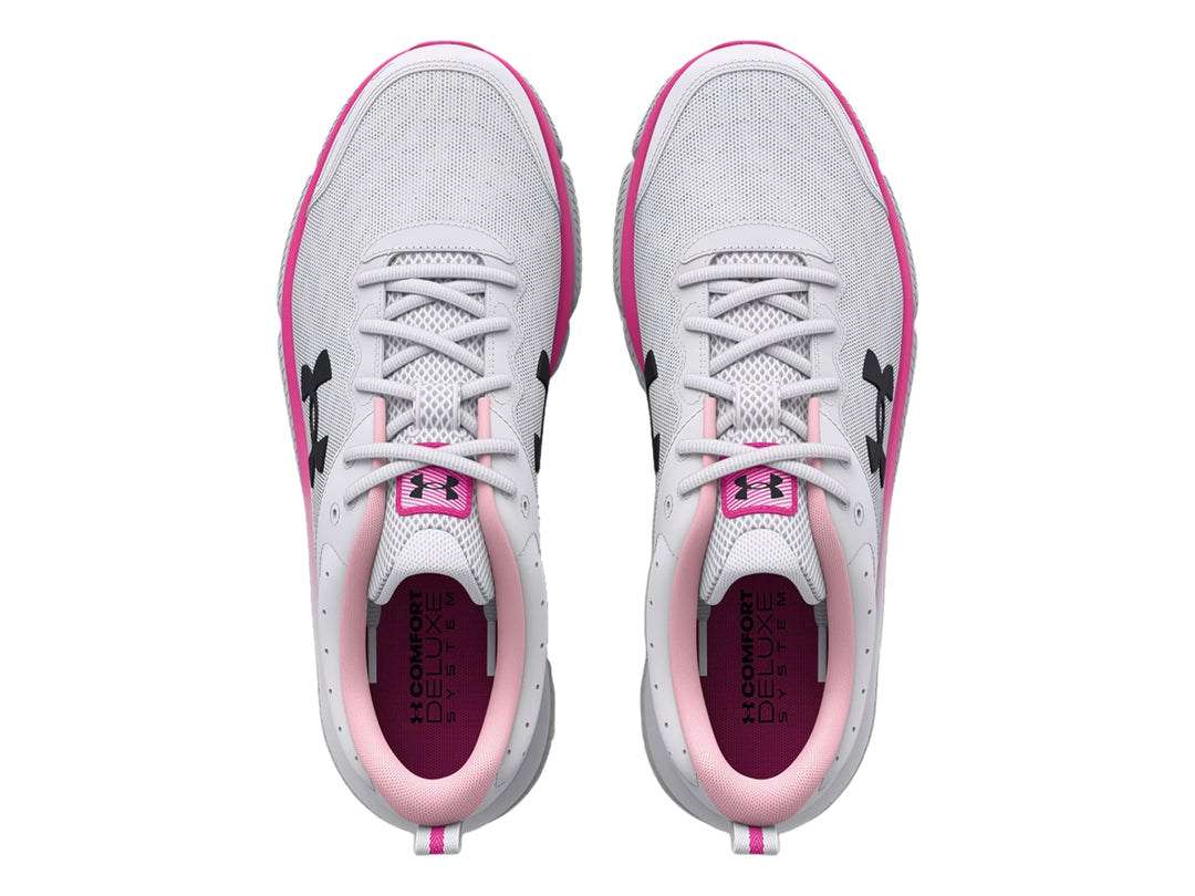 Tenis deportivos Under Armour blancos con detalles en rosa y logo negro, vista lateral.
