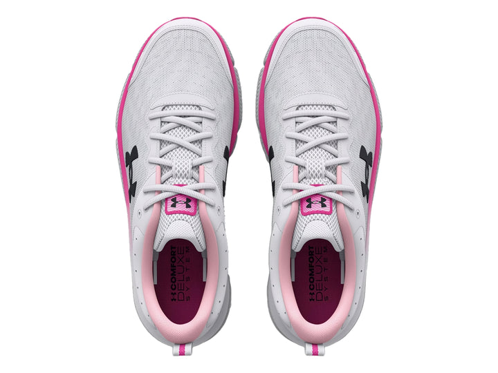 Tenis deportivos Under Armour blancos con detalles en rosa y logo negro, vista lateral.