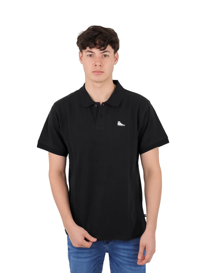 Hombre vistiendo una camiseta polo de manga corta color negro de la marca Converse.