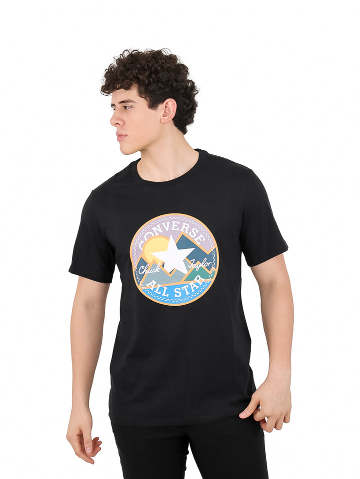 Hombre vistiendo camiseta negra de manga corta con estampado circular de Converse All Star en el pecho.