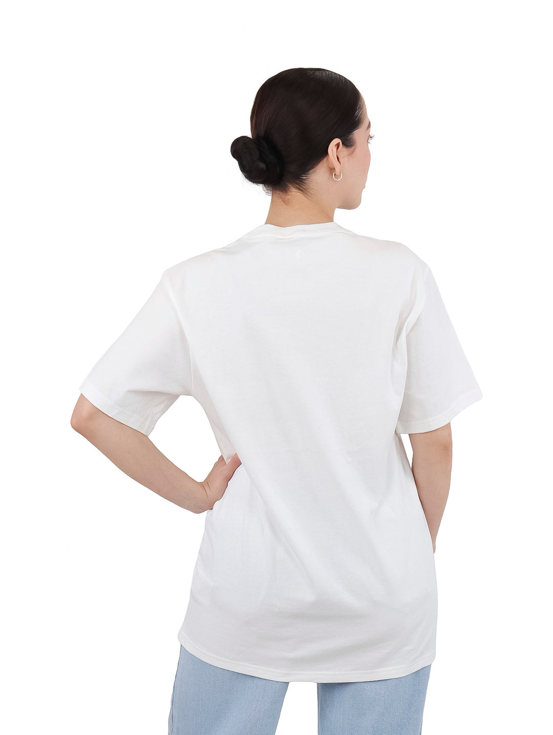 Mujer vistiendo una camiseta blanca de manga corta con un estampado circular colorido en el pecho.