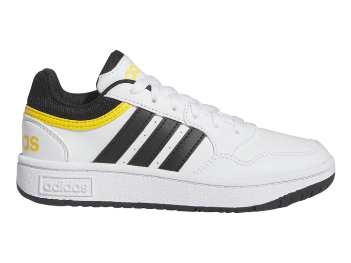 Tenis Adidas blancos con tres franjas negras y detalles en amarillo.