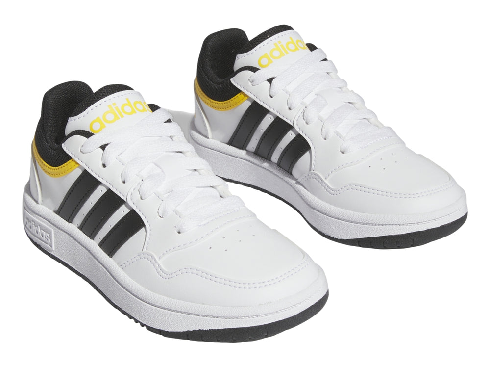 Tenis Adidas blancos con tres franjas negras y detalles en amarillo.