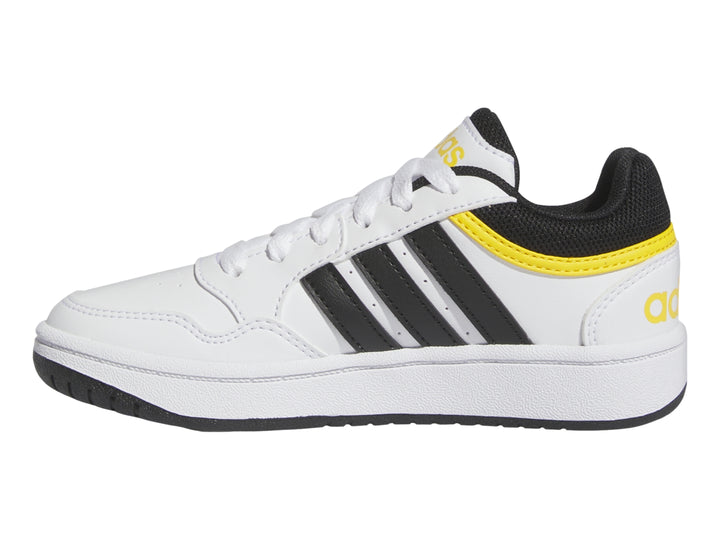 Tenis Adidas blancos con tres franjas negras y detalles en amarillo.