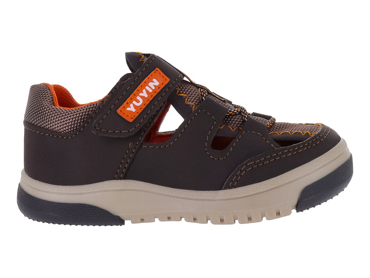 Sandalia infantil cerrada color chocolate con suela beige y detalles naranjas.