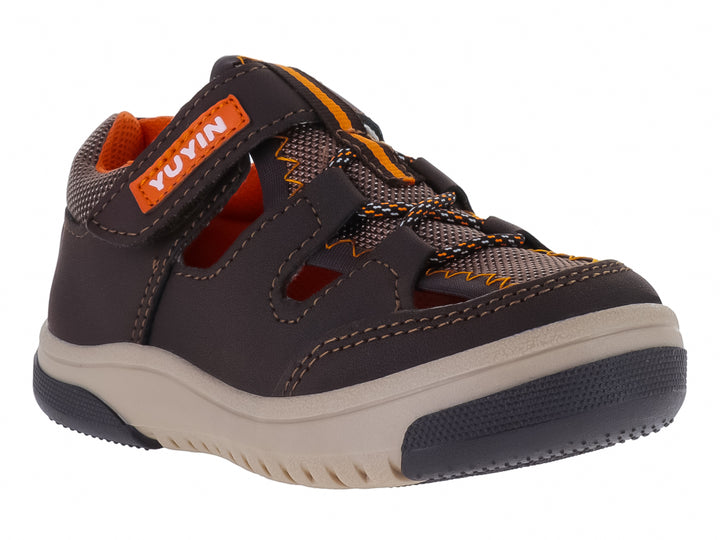 Sandalia infantil cerrada color chocolate con suela beige y detalles naranjas.