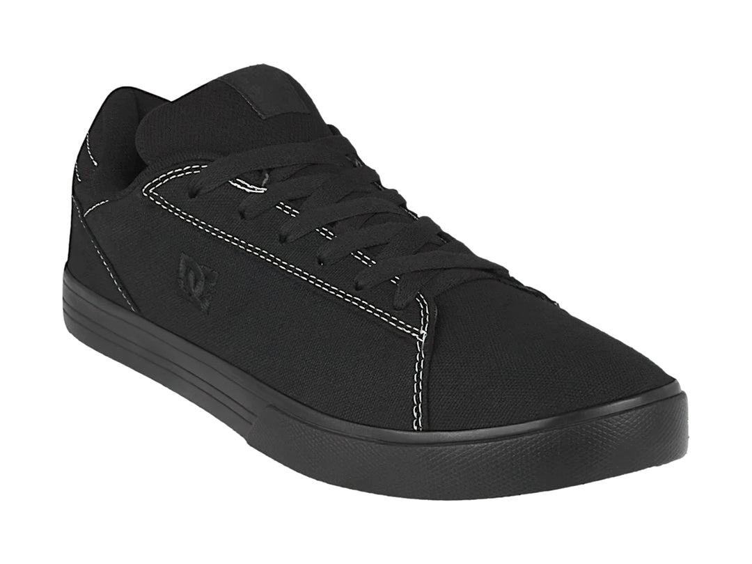 Tenis negros de tela marca DC Shoes con costuras blancas y suela plana.