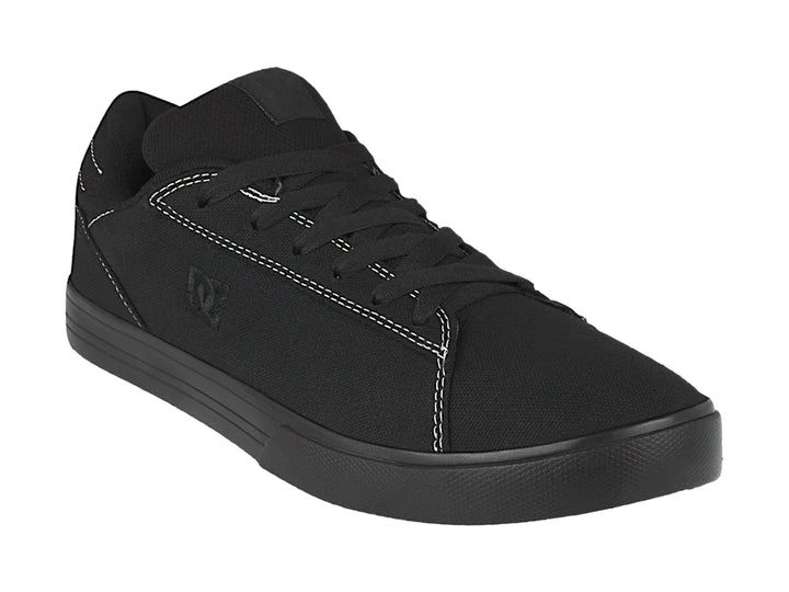Tenis negros de tela marca DC Shoes con costuras blancas y suela plana.