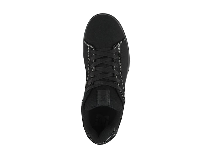 Tenis negros de tela marca DC Shoes con costuras blancas y suela plana.