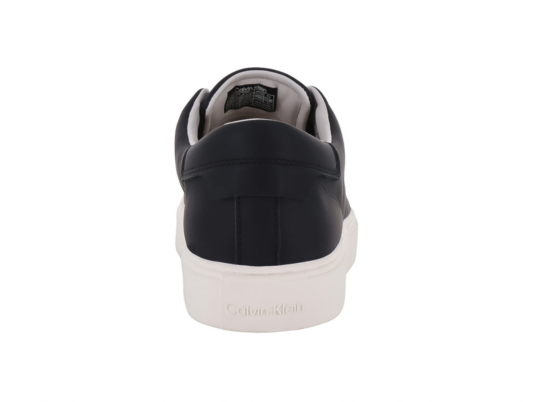 Tenis Calvin Klein de cuero negro con suela blanca y cordones, diseño minimalista y casual.