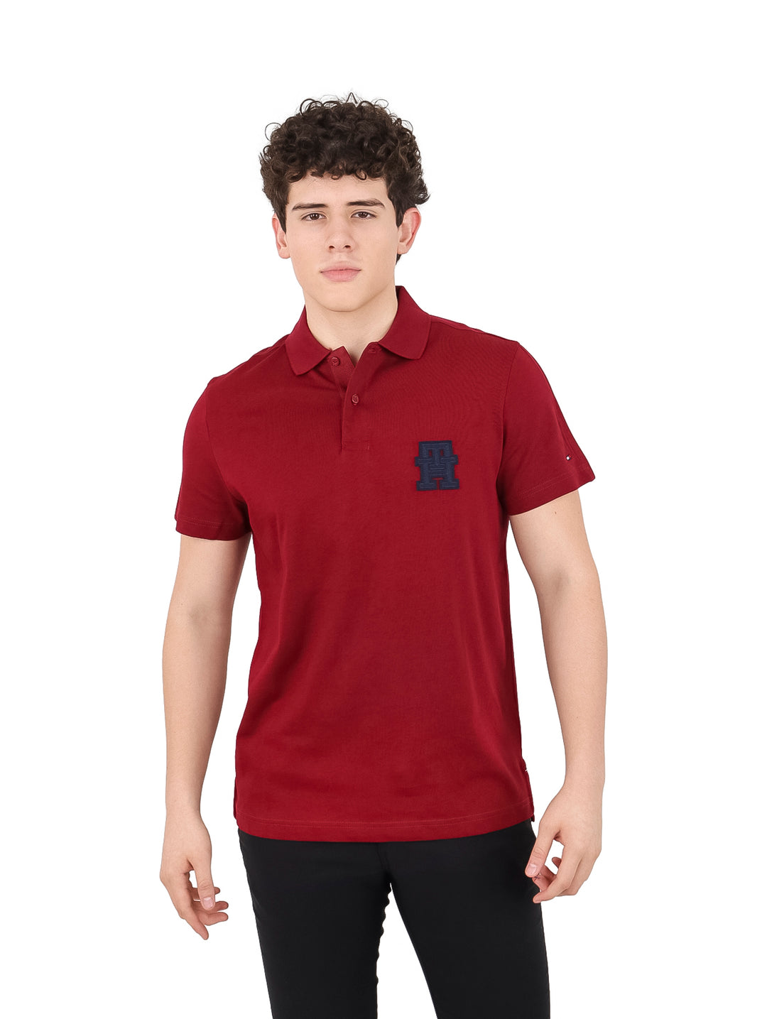 Hombre vistiendo una camiseta polo color burgundy de Tommy Hilfiger con monograma NY en el pecho.