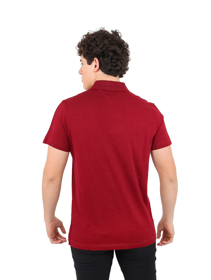 Hombre vistiendo una camiseta polo color burgundy de Tommy Hilfiger con monograma NY en el pecho.