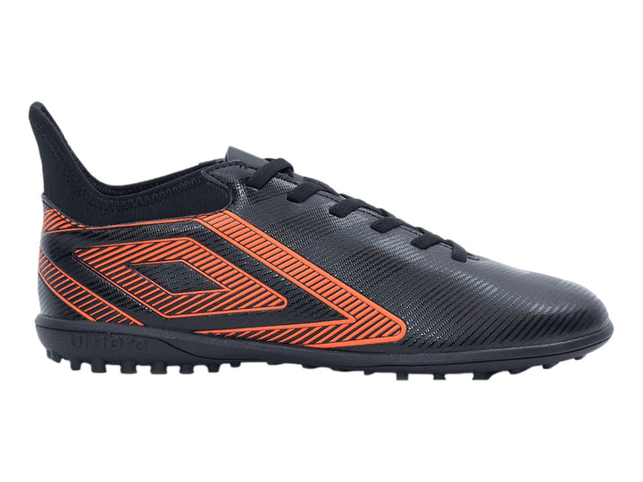 Zapato de fútbol Umbro negro con diseño geométrico naranja y suela para césped sintético.