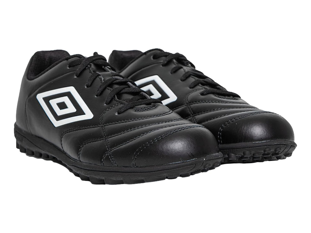 Zapato de fútbol Umbro color negro con logo blanco y suela para césped sintético.