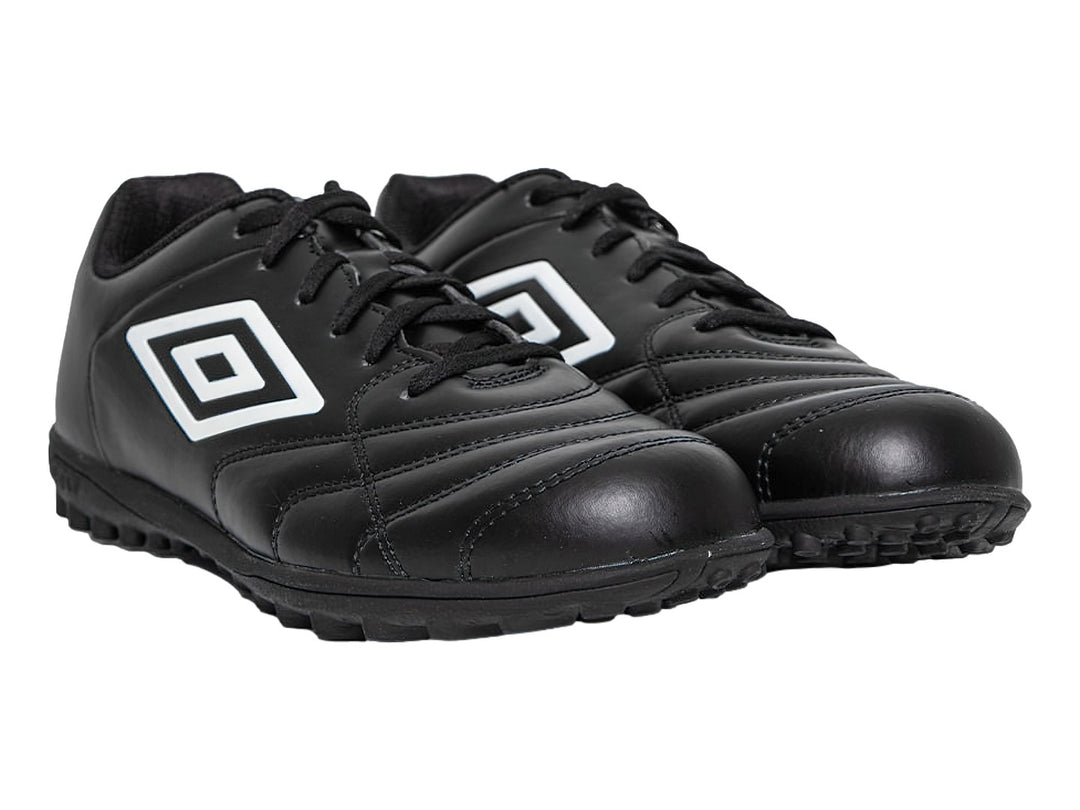 Zapato de fútbol Umbro color negro con logo blanco y suela para césped sintético.