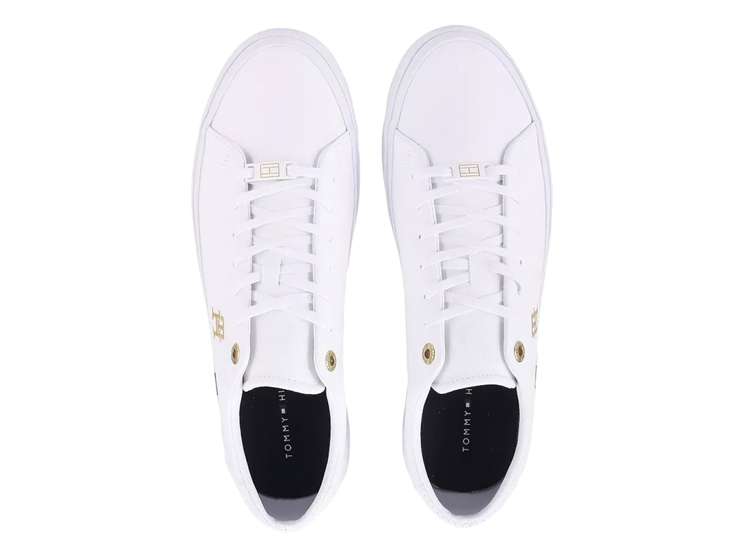 Tenis blancos Tommy Hilfiger de perfil bajo con detalles en dorado y franja roja, blanca y azul en la suela.